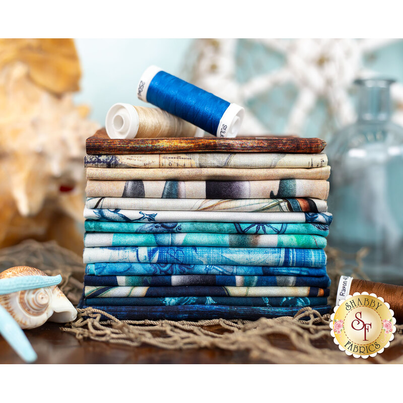 A stack of nautical themed fabrics surrounded by shells, netting and spools of thread.