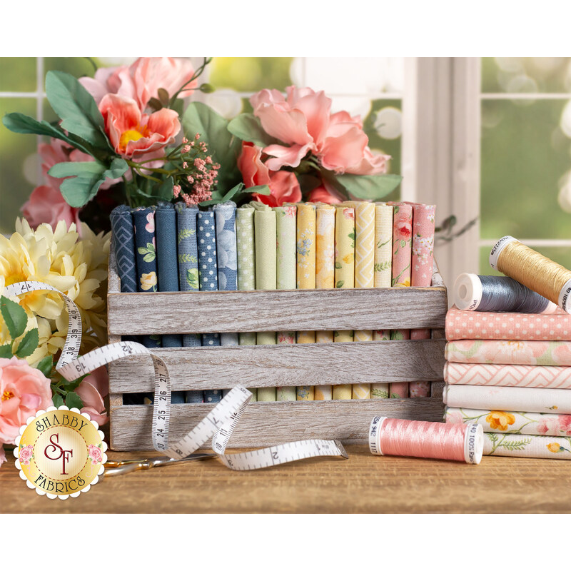 pink, yellow, green, and blue floral fabrics in a wood box surrounded by pink and yellow flowers