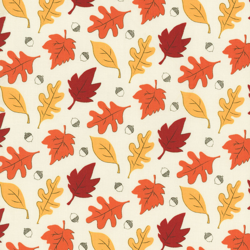 fabric featuring orange, yellow and red leaves and acorns on a rich cream background