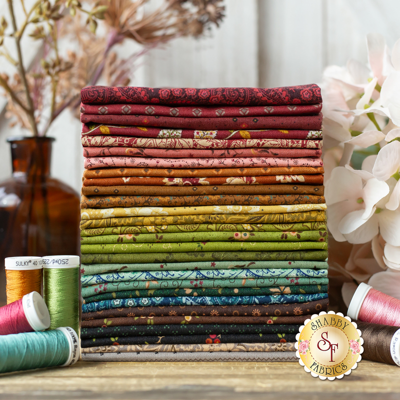 A photograph of the stack of fabrics included in the 28FQ set. The fabrics are staged with coordinating flowers and spools of threads.