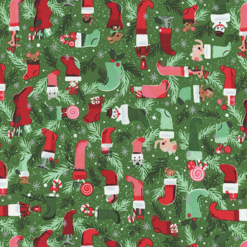 This fabric features red and green tonal Christmas stockings with toys and boughs on a green background with metallic silver accents.