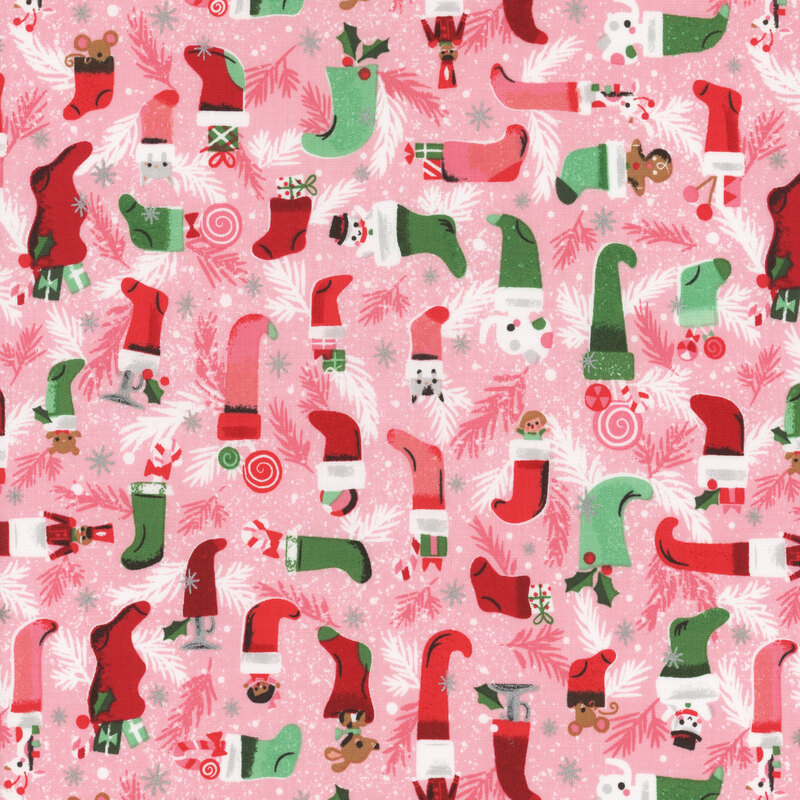 This fabric features red and green tonal Christmas stockings with toys and boughs on a light pink background with metallic silver accents.