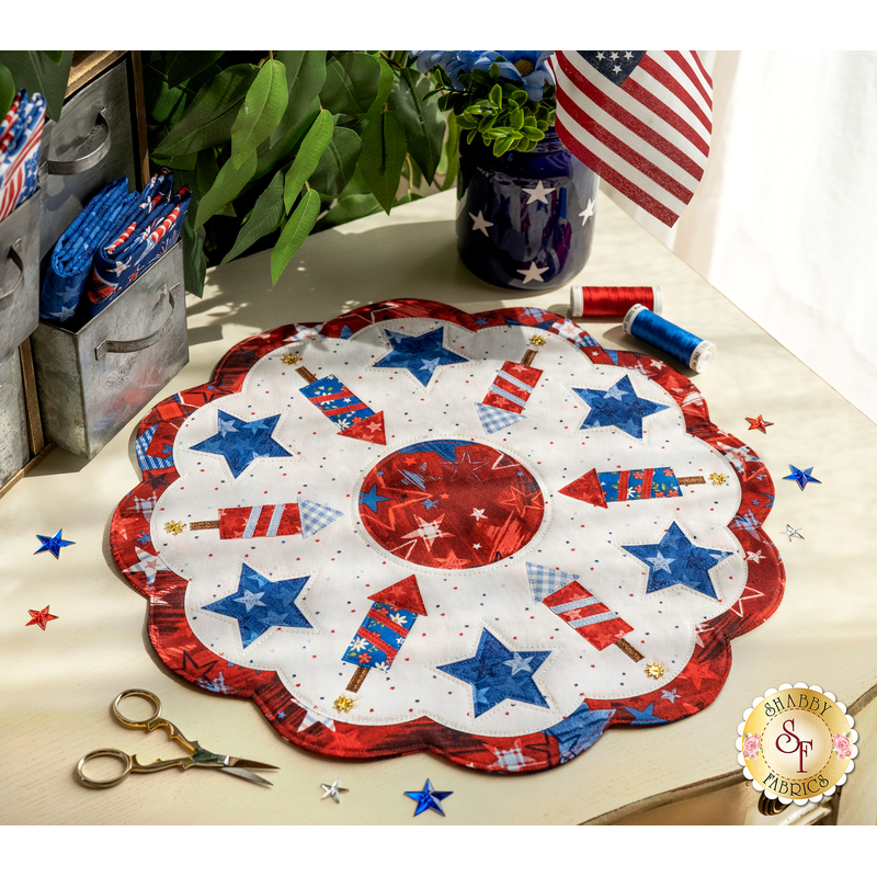 A patriotic red, white, and blue scalloped table topper with stars and fireworks