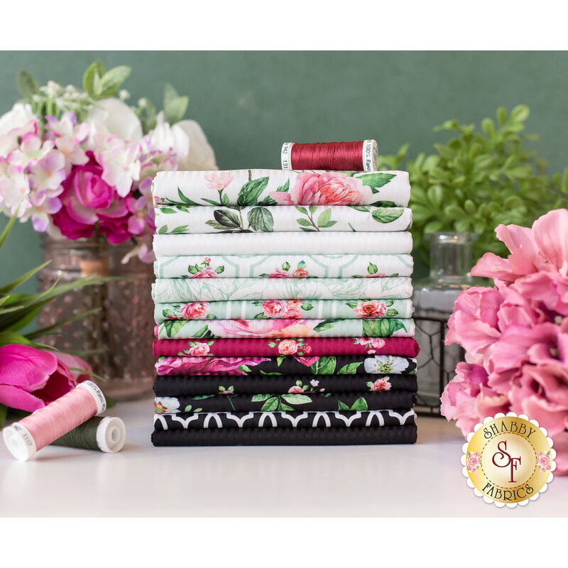 white, mint, magenta, and black floral fabric stacked on a table surrounded by flowers