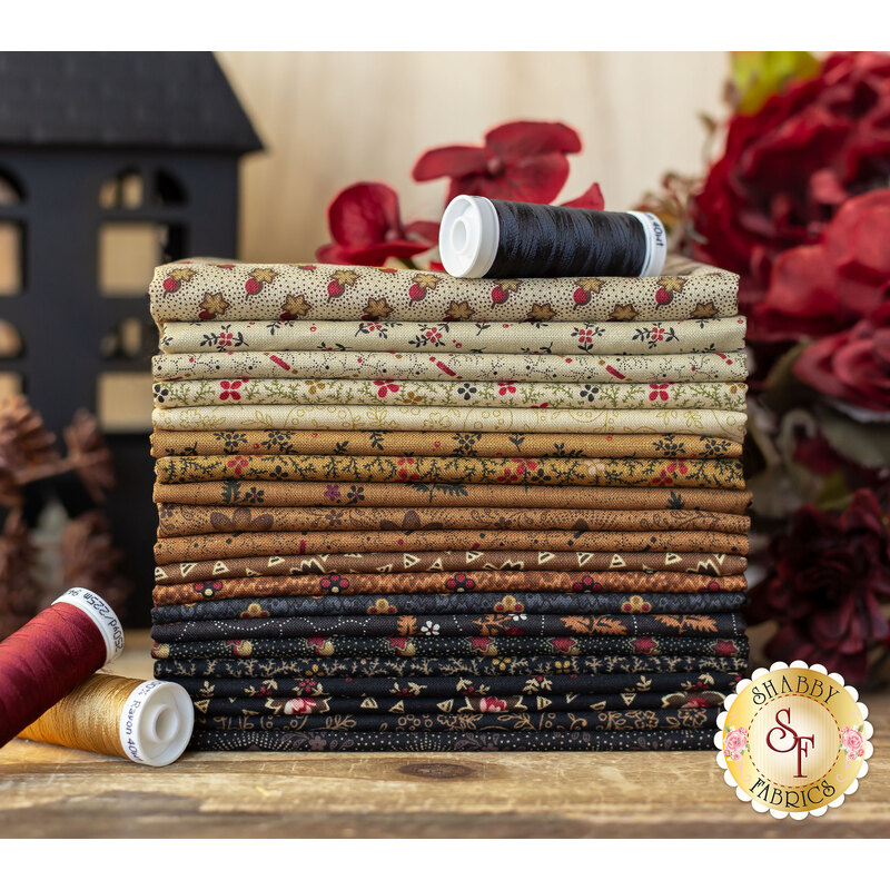 cream, tan, and dark brown and black fabrics with red floral accents stacked on a wood table
