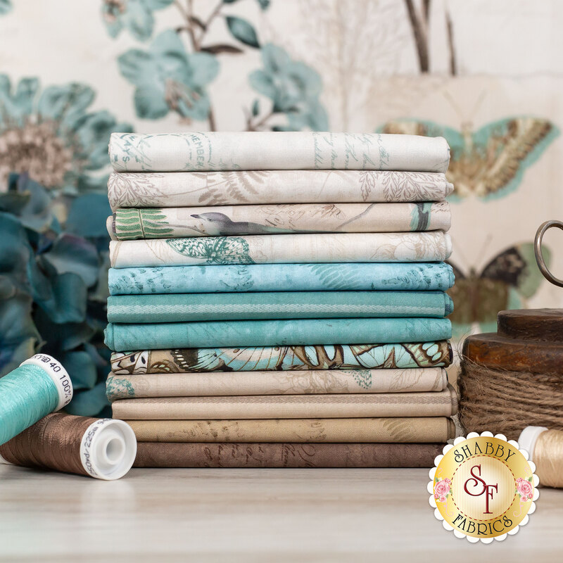 stack of cream, teal, tan, and brown fabrics from the En Bleu collection, with the En Bleu panel in the background