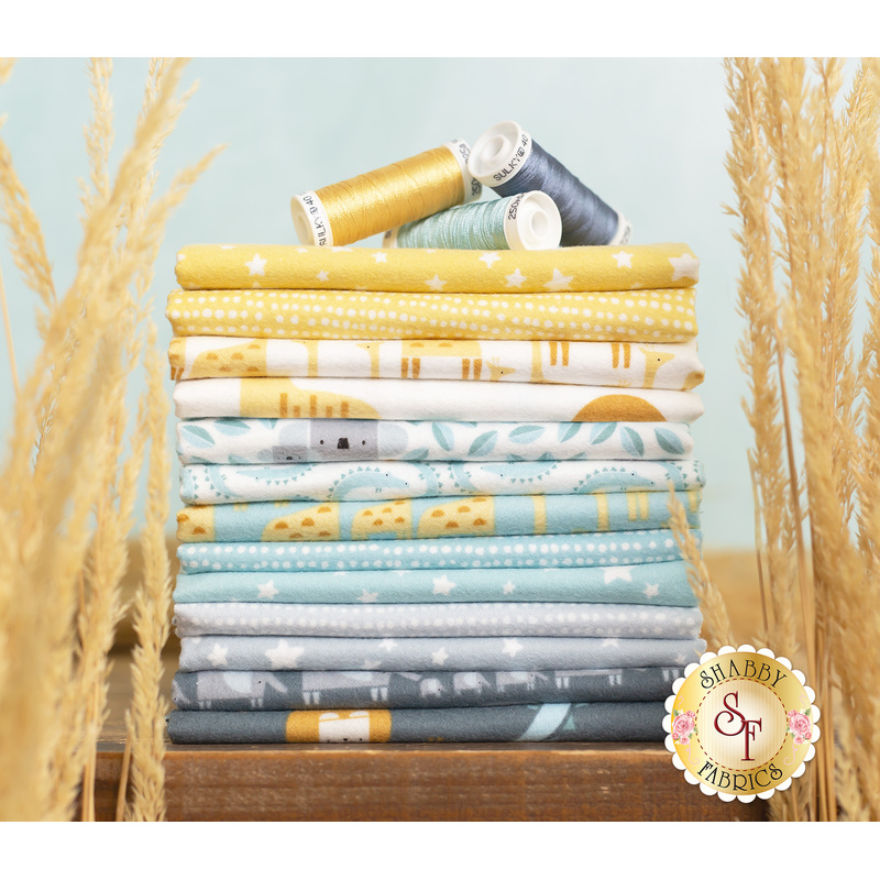 Stack of yellow, blue, and grey fabric featuring geometric animals, surrounded by tall dry grass.