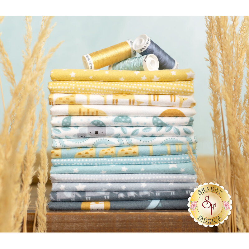 Stack of yellow, blue, and grey fabric featuring geometric animals, surrounded by tall dry grass.