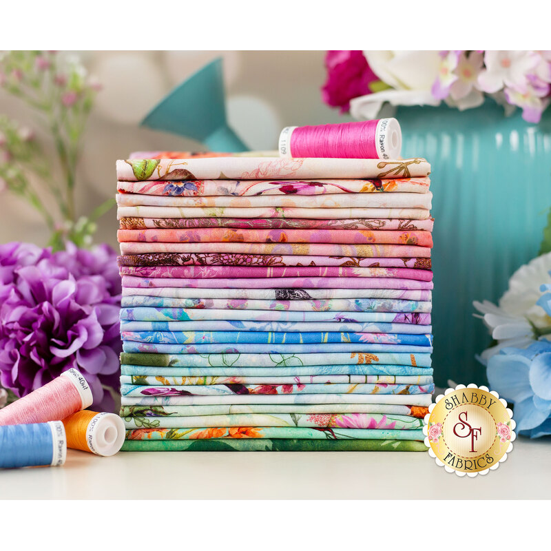 floral fabrics in a pastel rainbow stacked on a table with thread and flowers