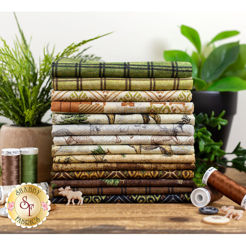 wildlife themed brown, cream, and green fabrics stacked on a table with plants, buttons, and thread
