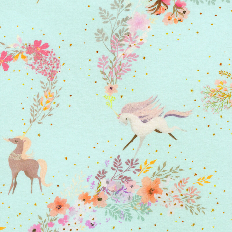 light blue fabric featuring various unicorns with a trail of warm colored flowers from the horn with scattered stars