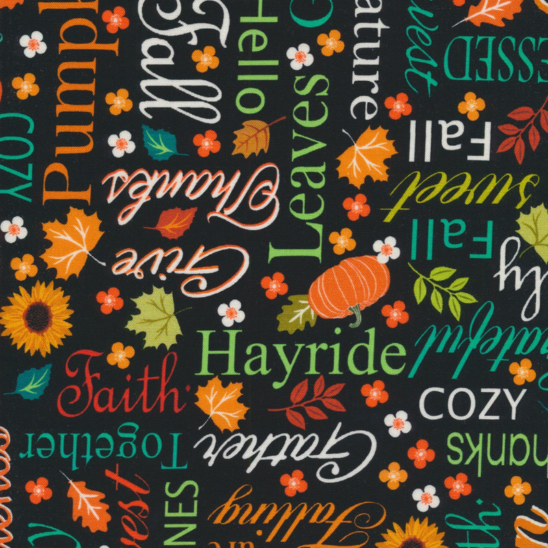 black fabric featuring a lovely array of varying fonts and colors of autumnal words and sayings, interspersed with fall leaves, pumpkins, and flowers