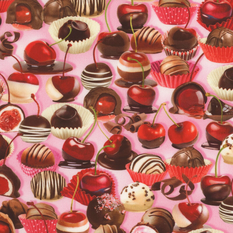 pink fabric featuring various chocolate covered cherries and cherry cordials, with chocolate curls scattered between them