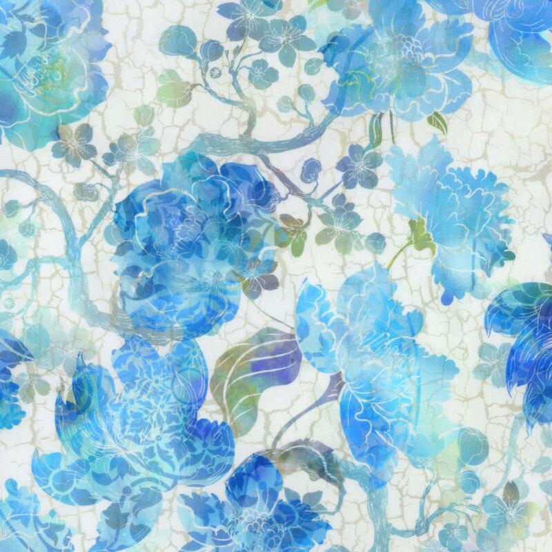 cream fabric featuring a crackled background with mottled green and blue blossoming branches and vivid mottled flowers in shades of blue