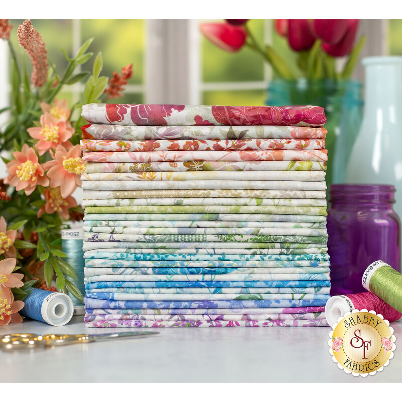 floral fabrics ranging from green to blue to purple to red, stacked on a table surrounded by flowers