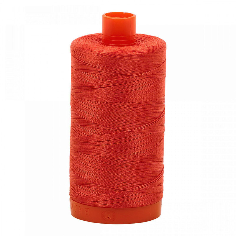 A spool of Aurifil 2277 - Light Red Orange thread on a white background