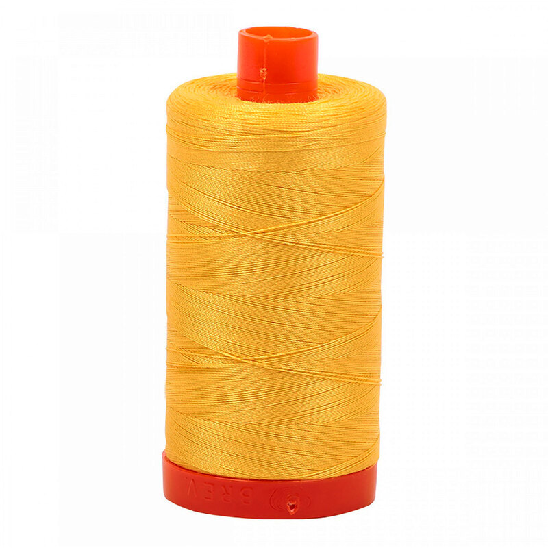 A spool of Aurifil 1135 - Pale Yellow thread on a white background