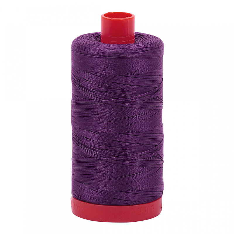 A spool of Aurifil 2582 - Dark Violet thread on a white background