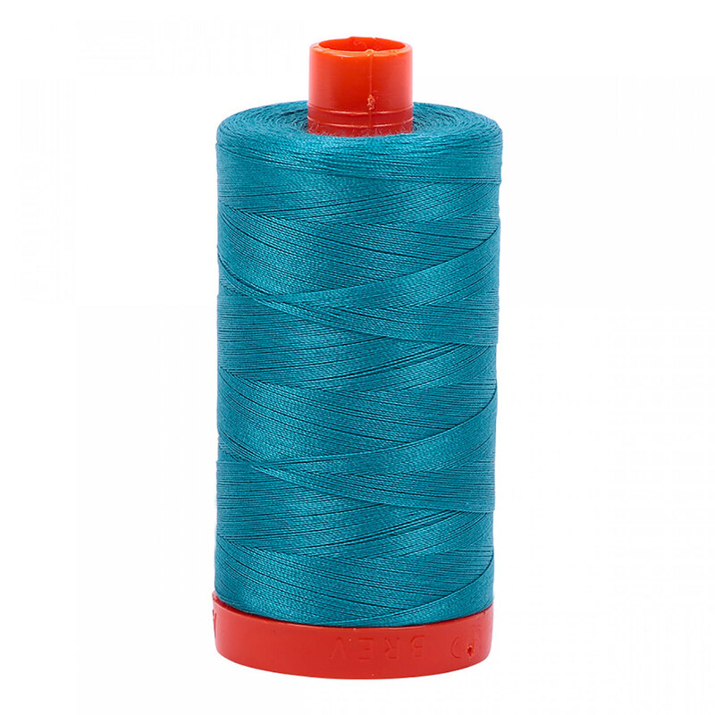 A spool of Aurifil 4182 - Dark Turquoise thread on a white background