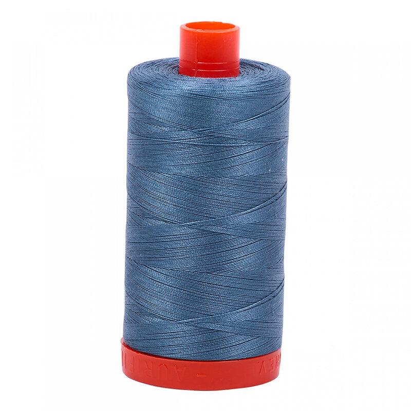 A spool of Aurifil 1126 - Blue Grey thread on a white background