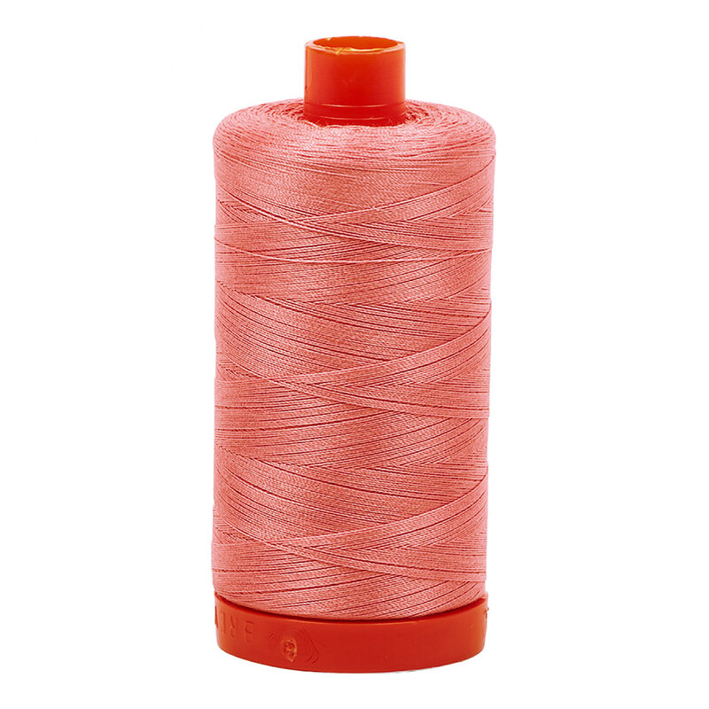 A spool of Aurifil 2435 - Peachy Pink thread on a white background