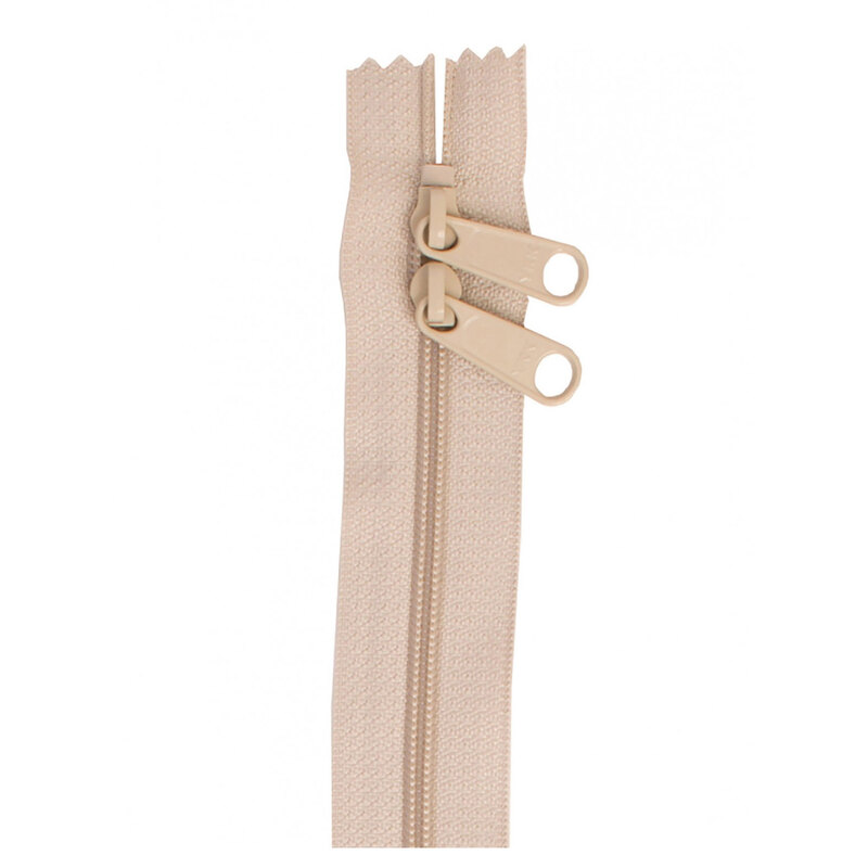 Photo of a beige zipper with two pull tabs isolated on a white background