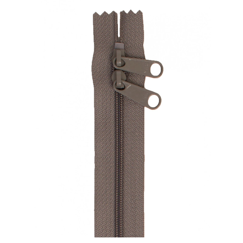 Photo of a gray-brown zipper with two pull tabs isolated on a white background