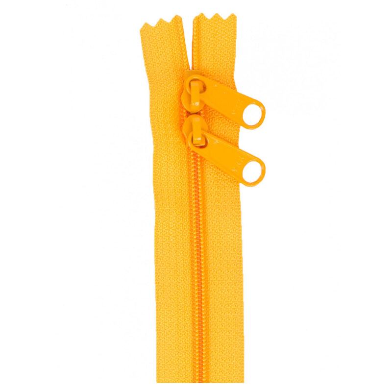 Photo of a light orange zipper with two pull tabs isolated on a white background