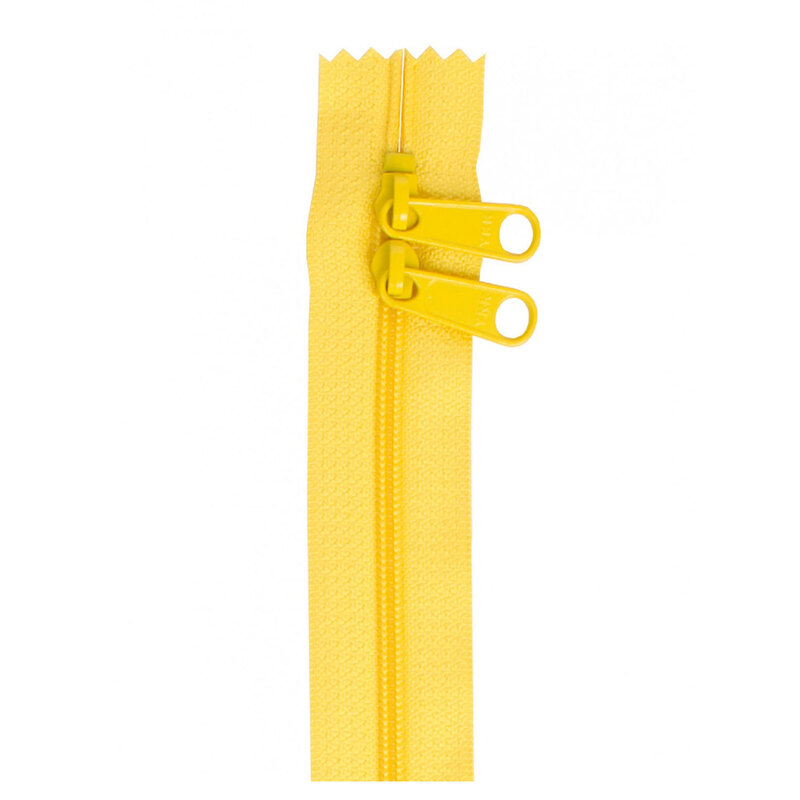 Photo of a yellow zipper with two pull tabs isolated on a white background