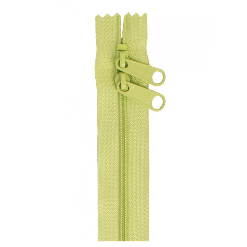 Photo of a light green zipper with two pull tabs isolated on a white background