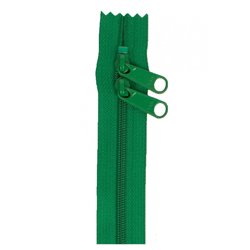 Photo of a dark green zipper with two pull tabs isolated on a white background
