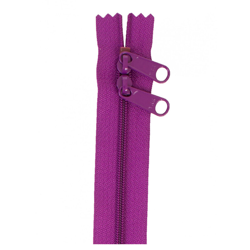 Photo of a bright purple zipper with two pull tabs isolated on a white background