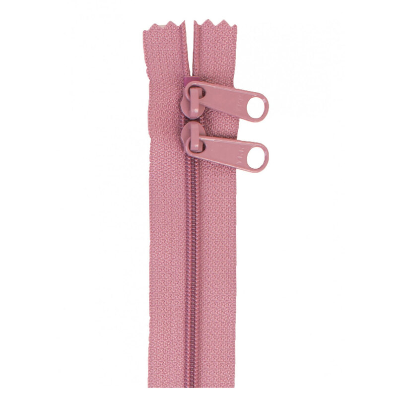 Photo of a dusty purple/pink zipper with two pull tabs isolated on a white background
