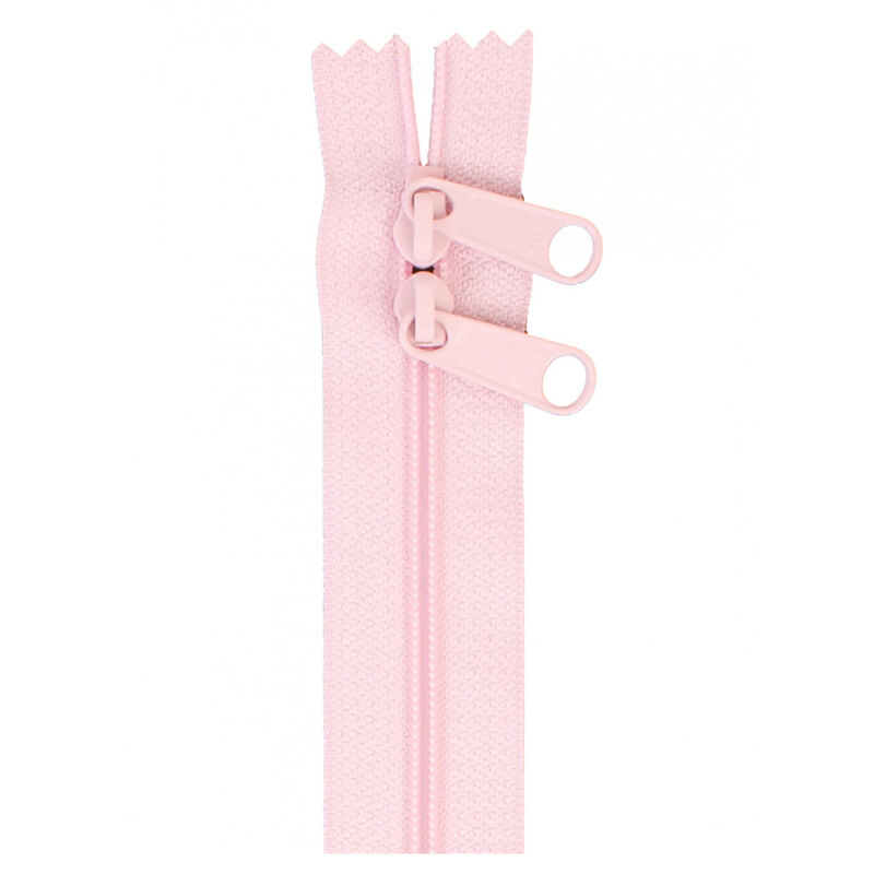 Photo of a light pink zipper with two pull tabs isolated on a white background