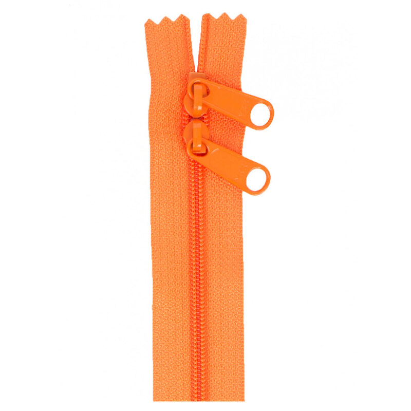 Photo of an orange zipper with two pull tabs isolated on a white background