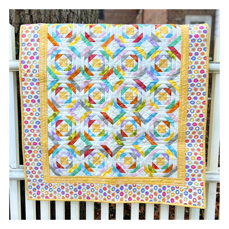 Photograph of multicolor geometric quilt hung over a banister