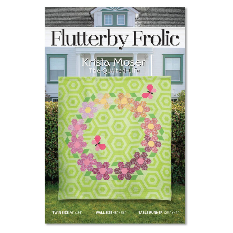 Front of the flutterby frolic quilt pattern displaying a photo of a green square quilt with hexagonal patterning and flowers and butterflies across it