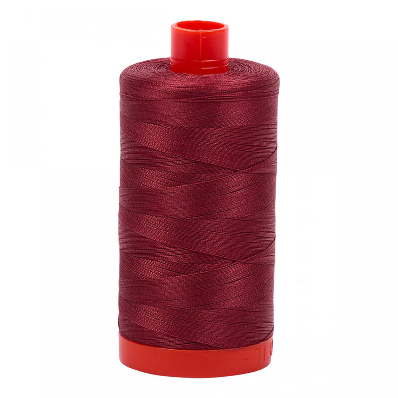 A spool of Aurifil 2345 - Raisin thread on a white background, with tones of sundried brown and rust red