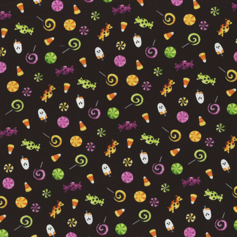 black fabric featuring scattered Halloween candy, such as candy corn, lollipops, and ghost popsicles