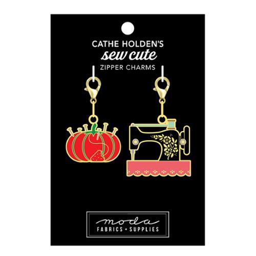 Image of a black tag with 2 sewing themed zipper pulls of a tomato pincushion and traditional sewing machine