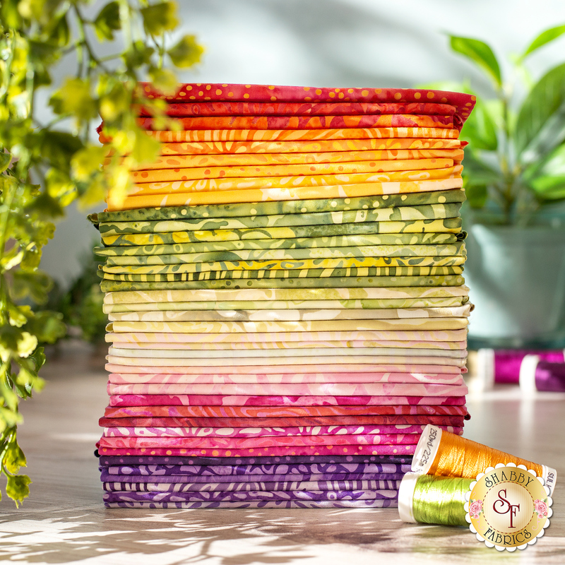 Beautiful photo of all the fat quarters included in the FQ set, folded into a neat stack and staged with coordinating thread sets and complementary foliage.