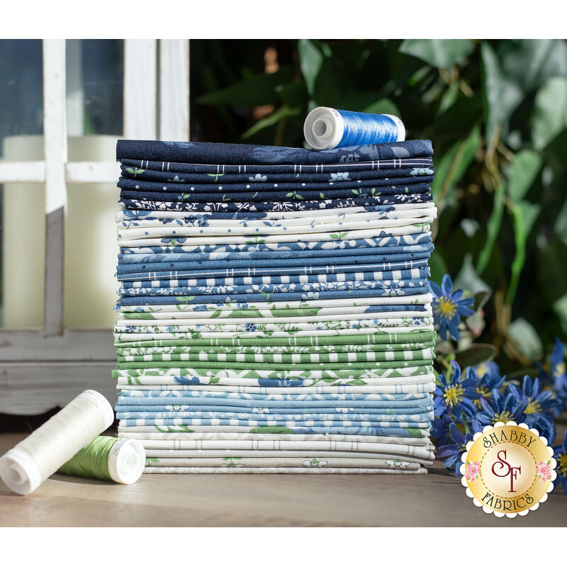 stack of shoreline fabrics, in shades of navy, blue, light blue, white, gray, and green, in lovely floral and tiled patterns