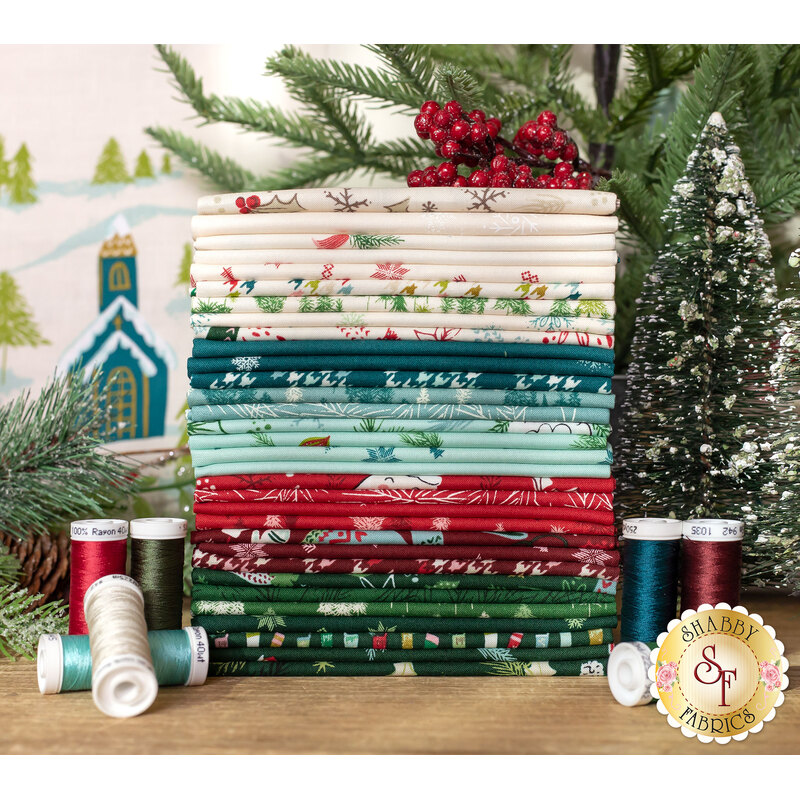 cozy wonderland fabric, in shades of red, dark red, dark blue, blue green, and creme, of Christmas themed designs and patterns surrounded by matching thread and decorative evergreens