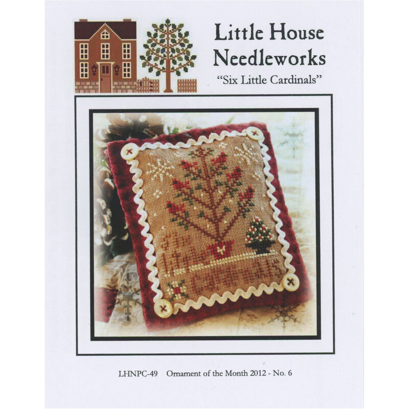 Front of pattern showing the completed small cross stitch ornament staged beside a pinecone atop a quilt