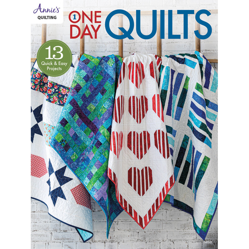 Front of One Day Quilts, showing four finished quilts hanging from a rack