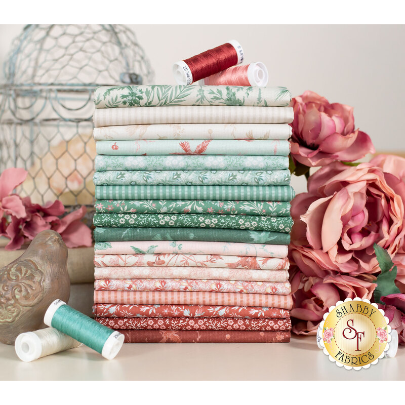 Pink and teal fabric with birds and flowers stacked on a cream table