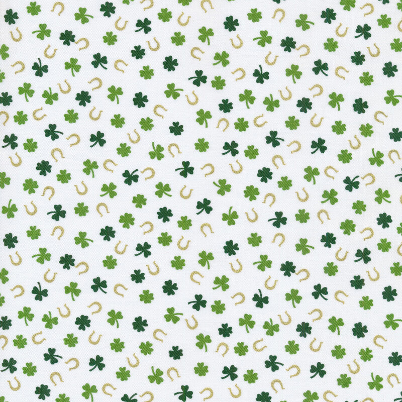 Green four leaf clovers and metallic gold horseshoes on white fabric.