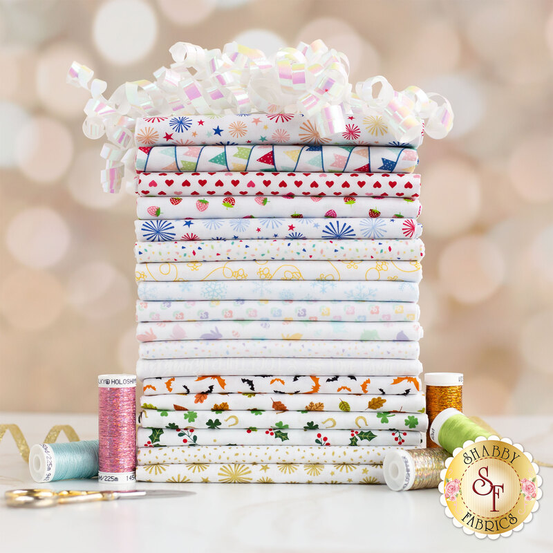 Colorful holiday prints on white fabric, stacked on a table with ribbon and thread