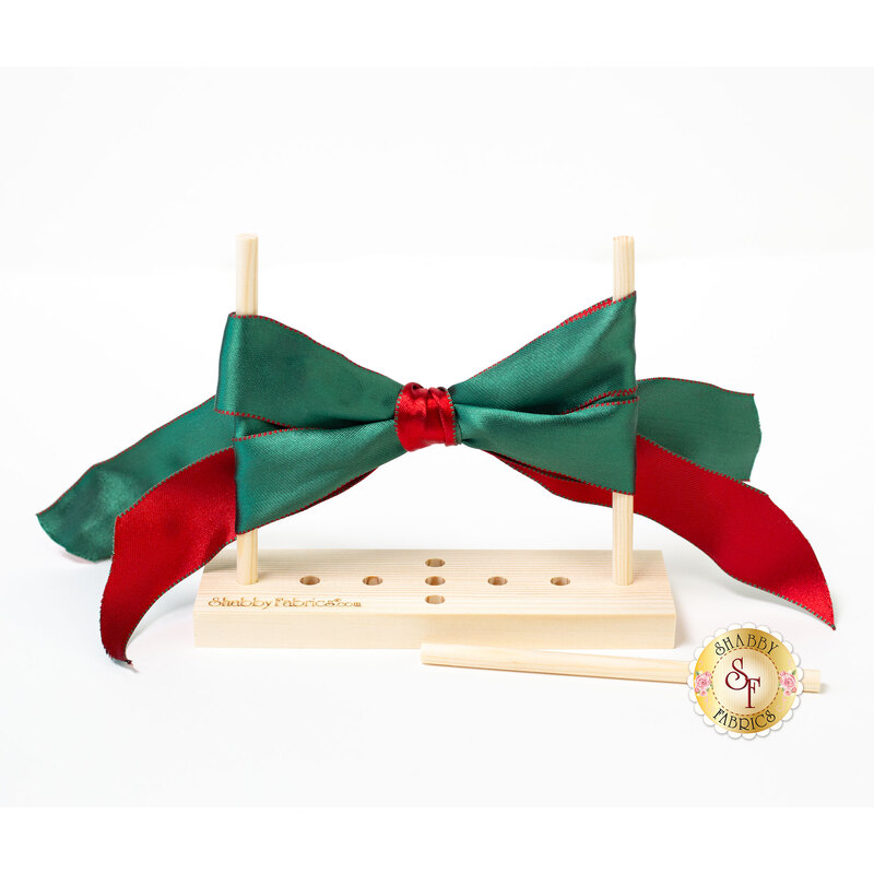 Photo of a red and green bow tied between two dowels on the bow maker