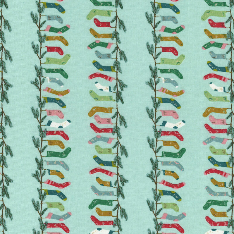 aqua fabric with rows of fir branches with hanging stockings in shades of pink, red, green, and aqua